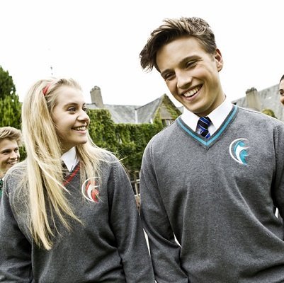 Students in grey school uniform sweaters with embroidered crest